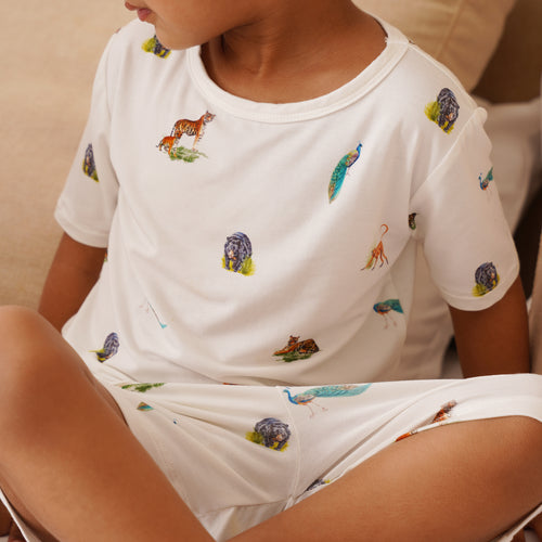 Child wearing a white pajama set with animal prints on a neutral background