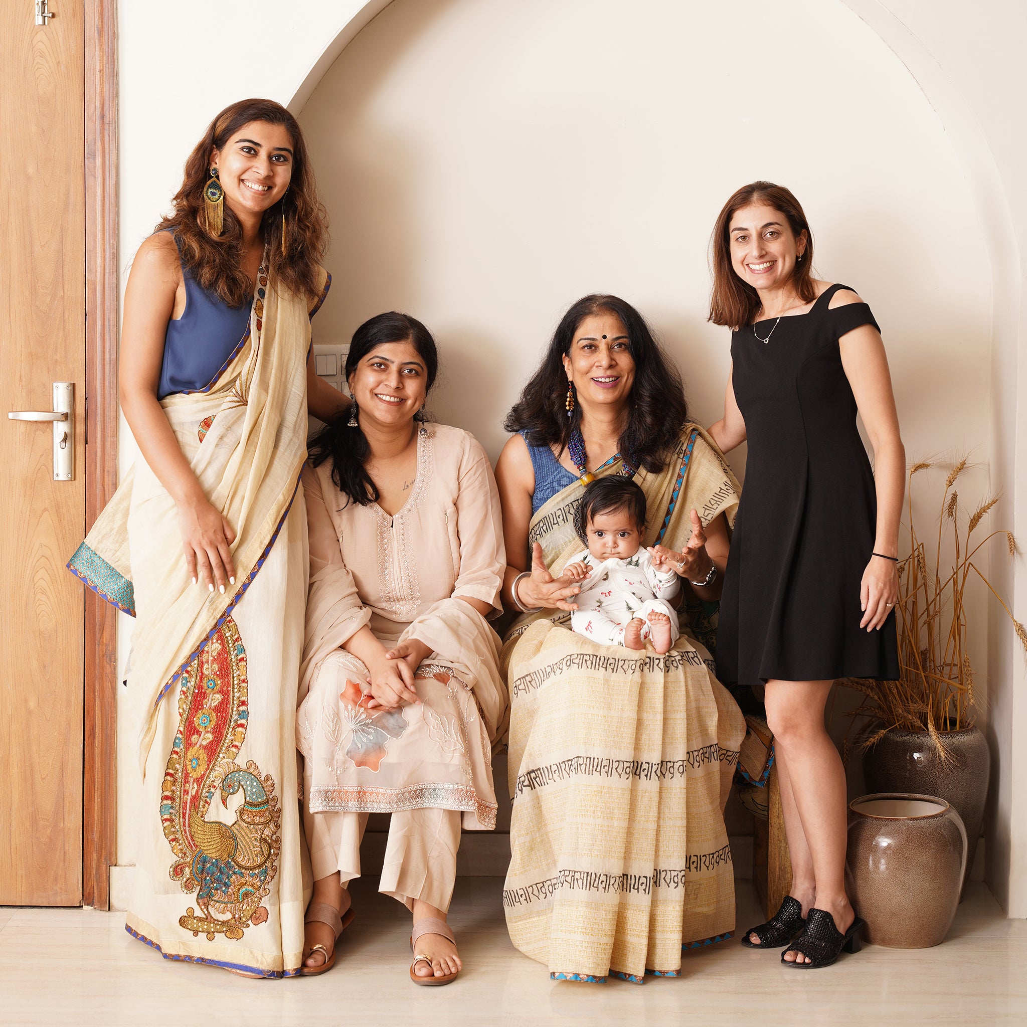 Group of women and a baby posing indoors with decorative elements.