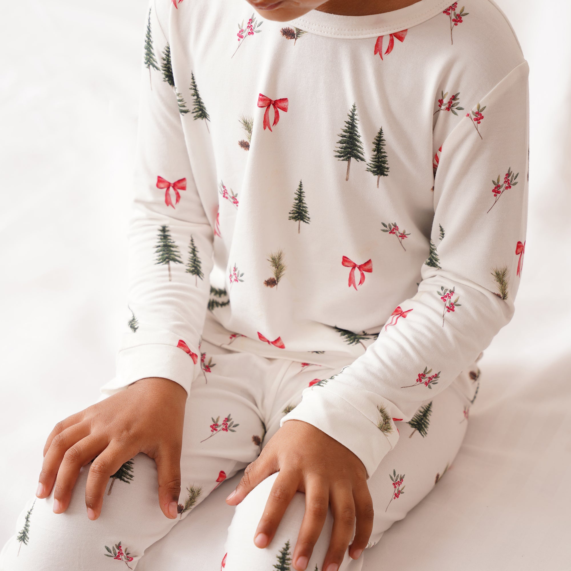 Children's pajama set with Christmas tree and bow pattern on a white background