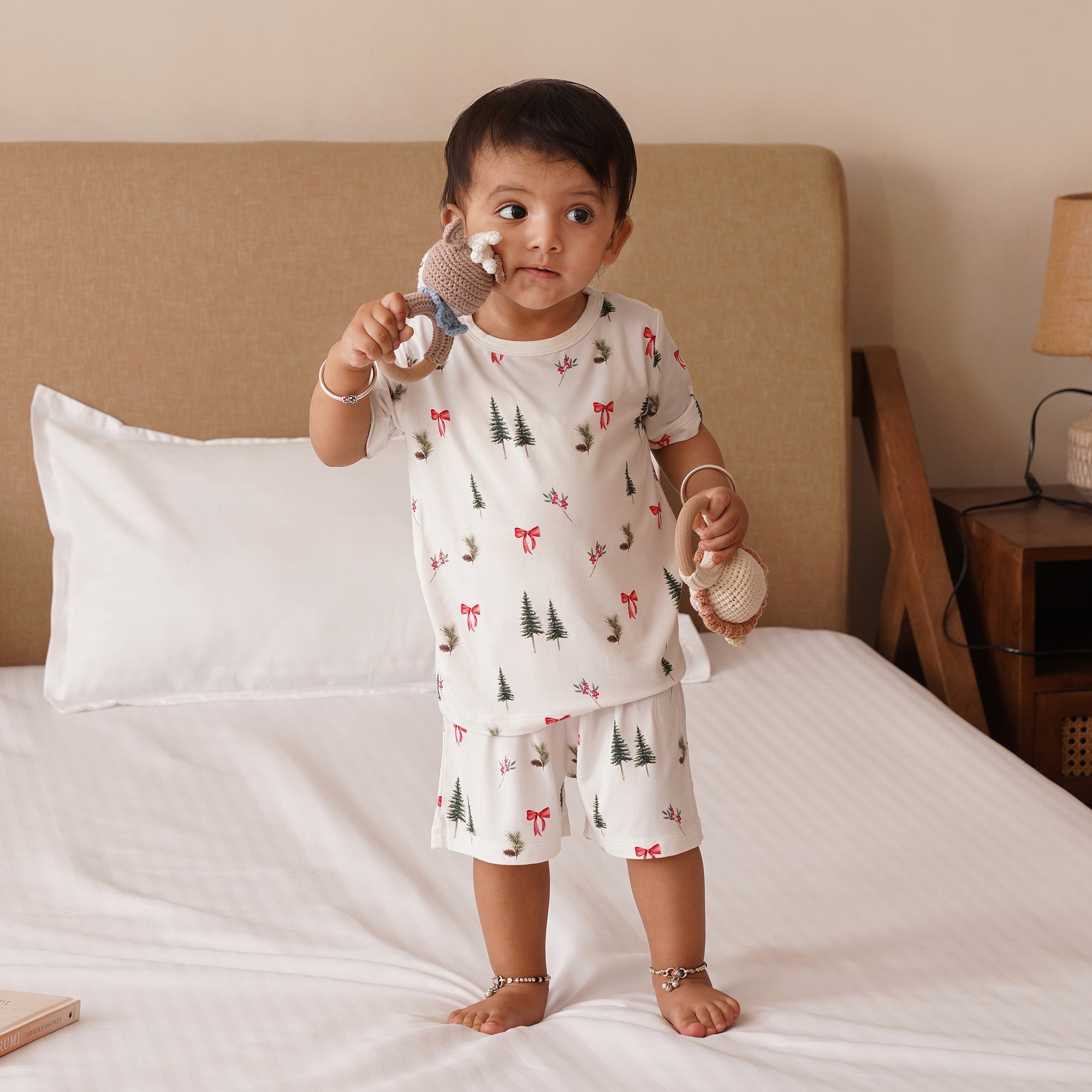 Child in pajamas holding baby rattles on a bed