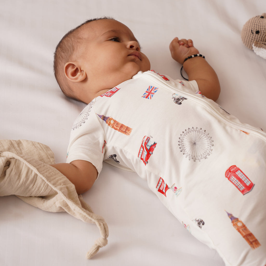 Baby wearing a london patterned shortie lying on a white surface
