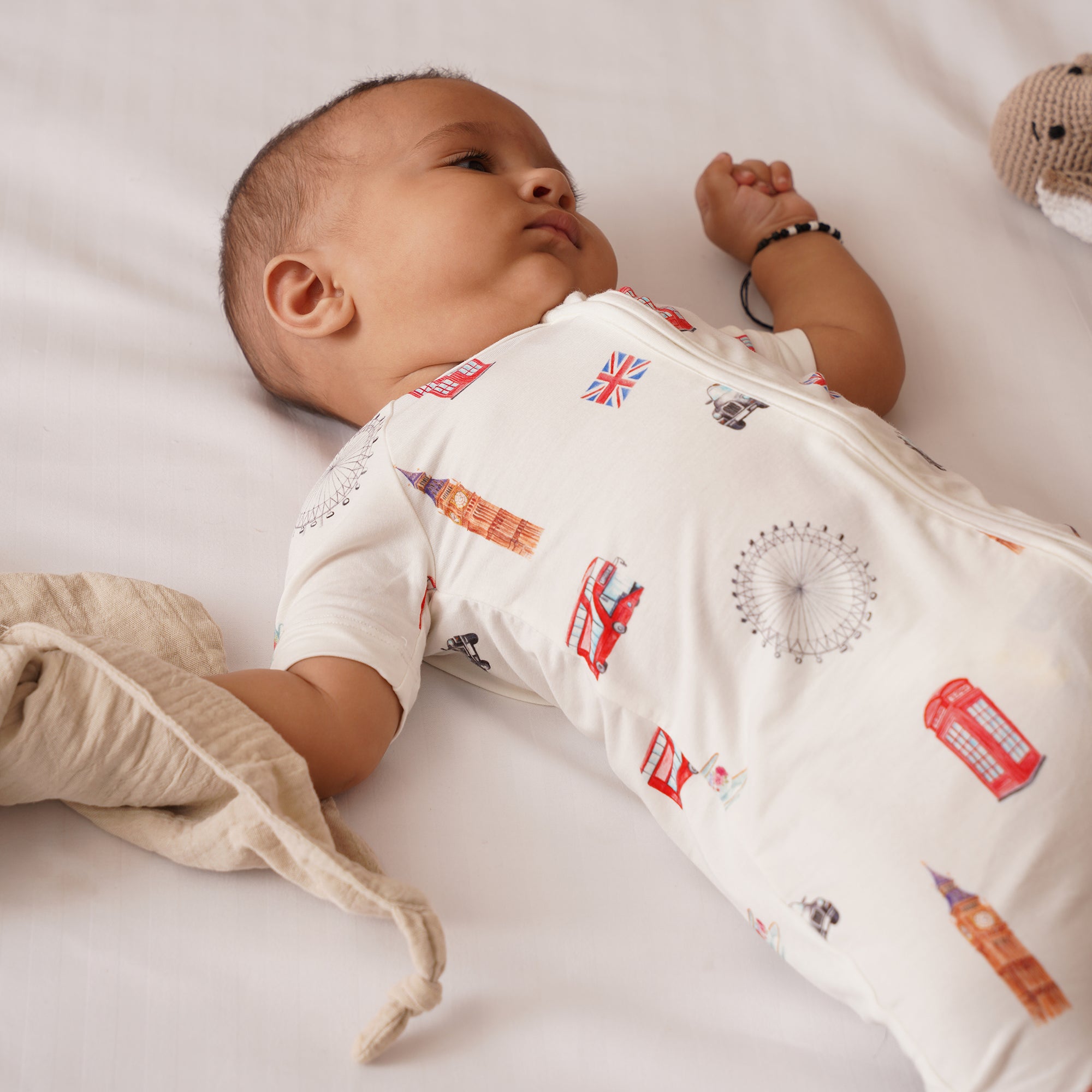 Baby wearing a london patterned shortie lying on a white surface