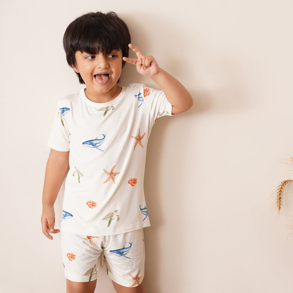Child wearing a white outfit with sea-themed patterns on a plain background