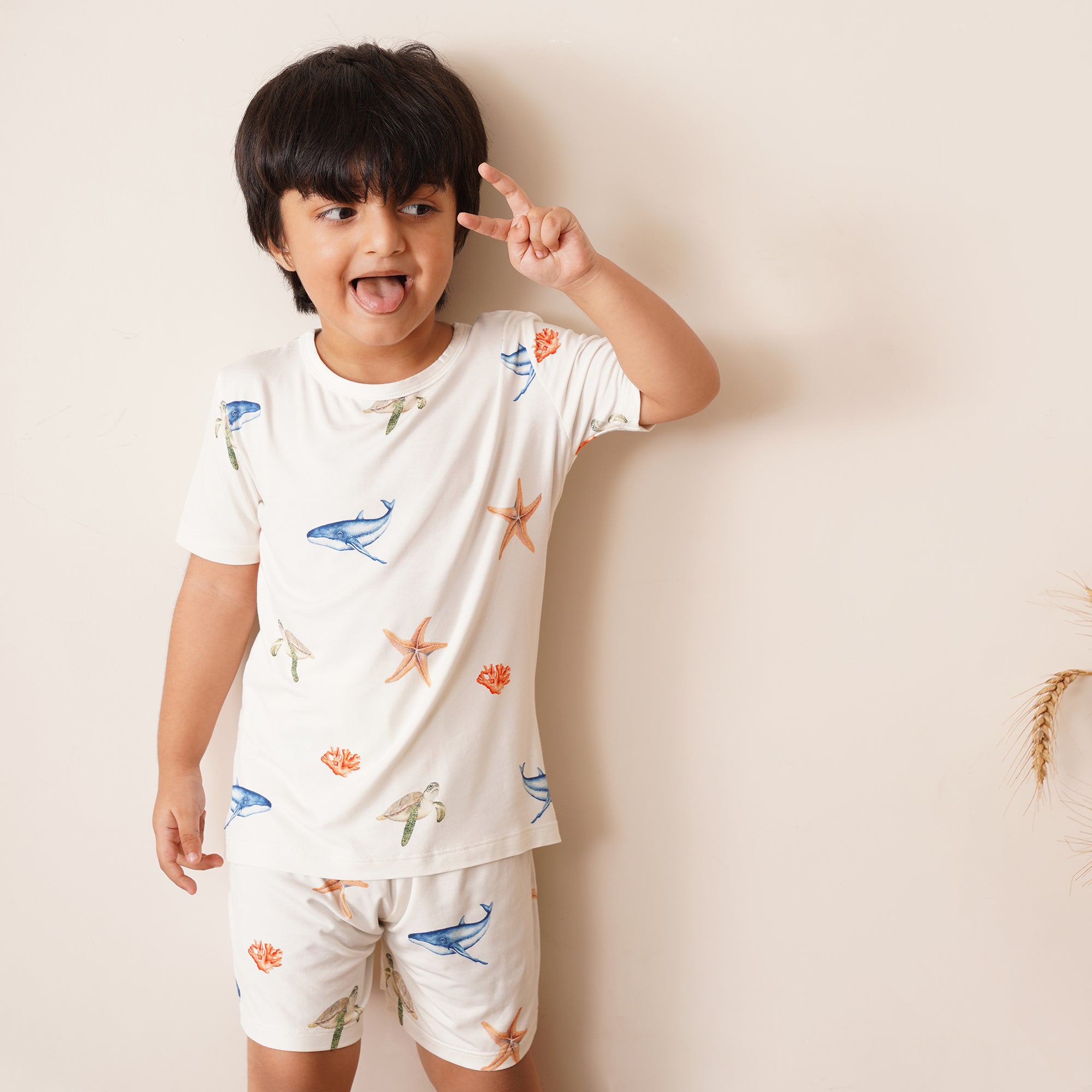 Child wearing a white outfit with sea-themed patterns on a plain background