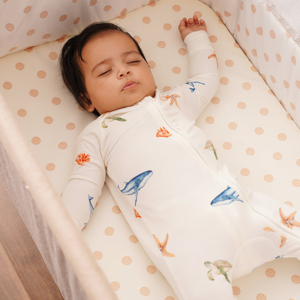 Baby sleeping in a crib with a under the sea zipsuit outfit